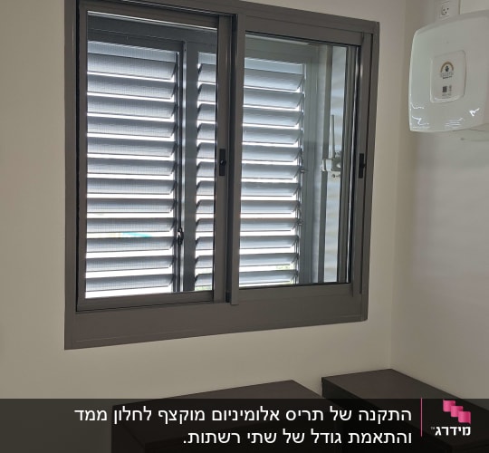 חלון הזזה מאלומיניום בגוון אפור כהה עם תריס בחדר ממ"ד